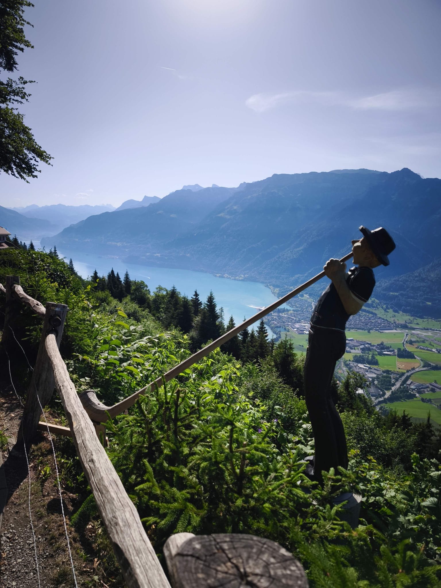 Alphorn statue overlooking turquoise Lake Brienz and Interlaken valley from a scenic viewpoint