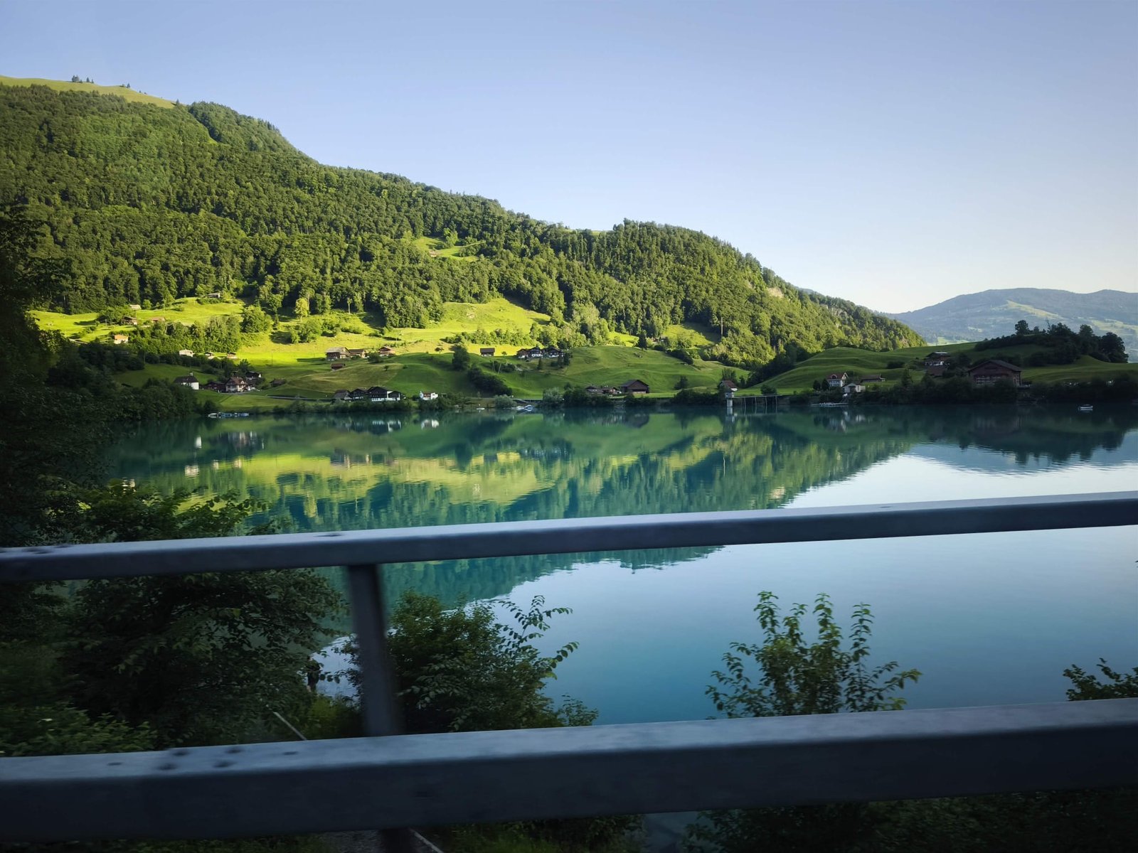Turquoise Lake Brienz reflecting green alpine hills and Swiss chalets on a day trip route