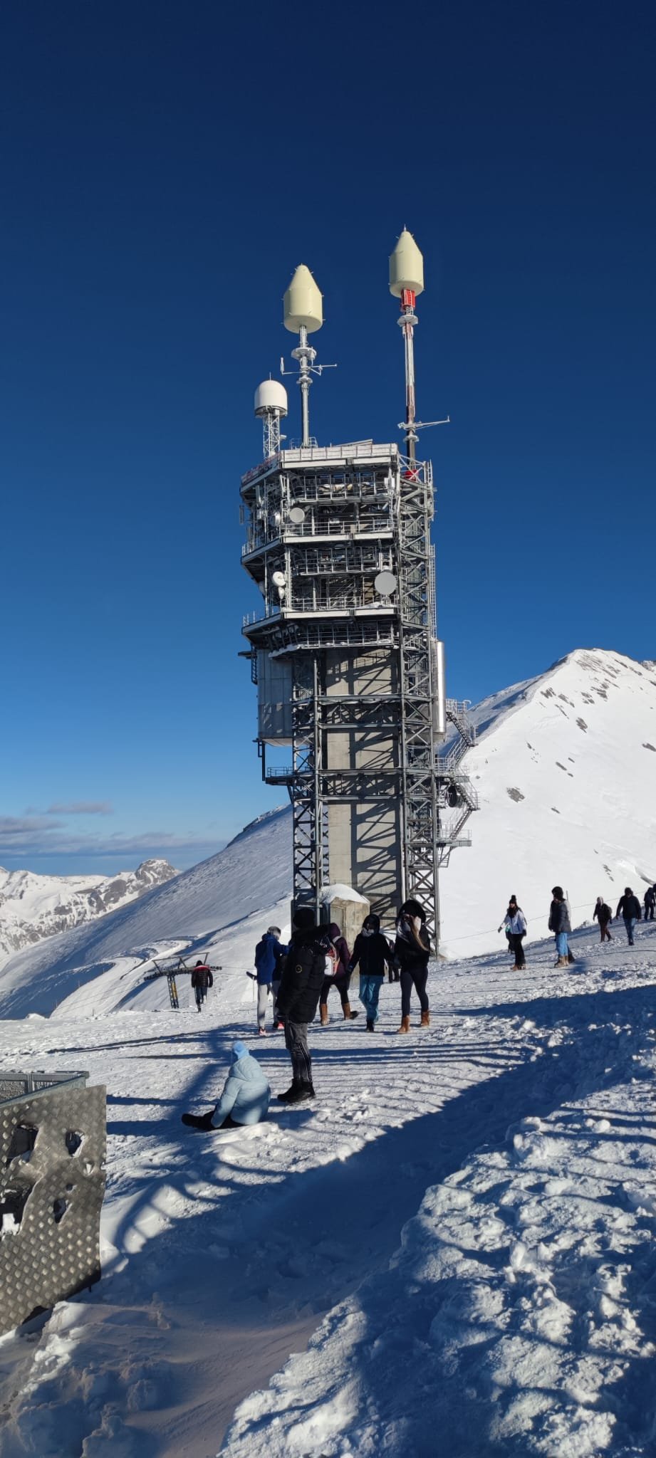 Mount Pilatus summit communication tower and snowy plateau with visitors in winter