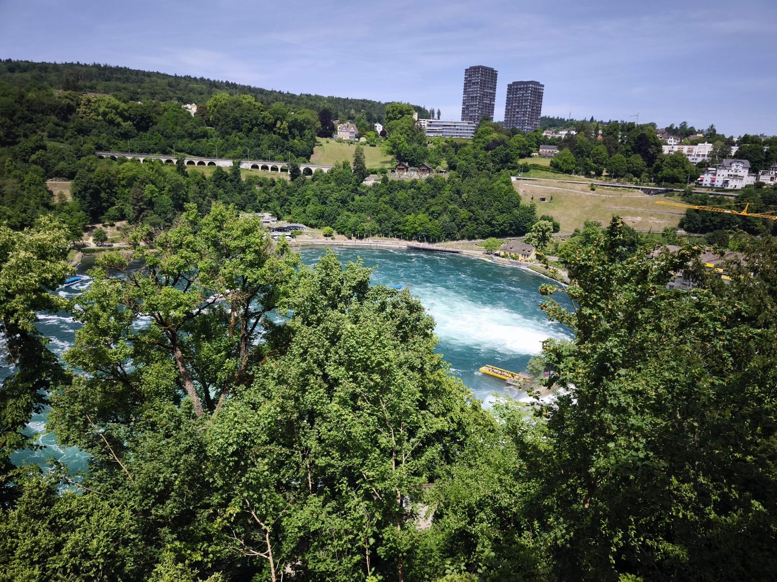 Rhine Falls and arched stone railway bridge on the forested hillside at Schaffhausen