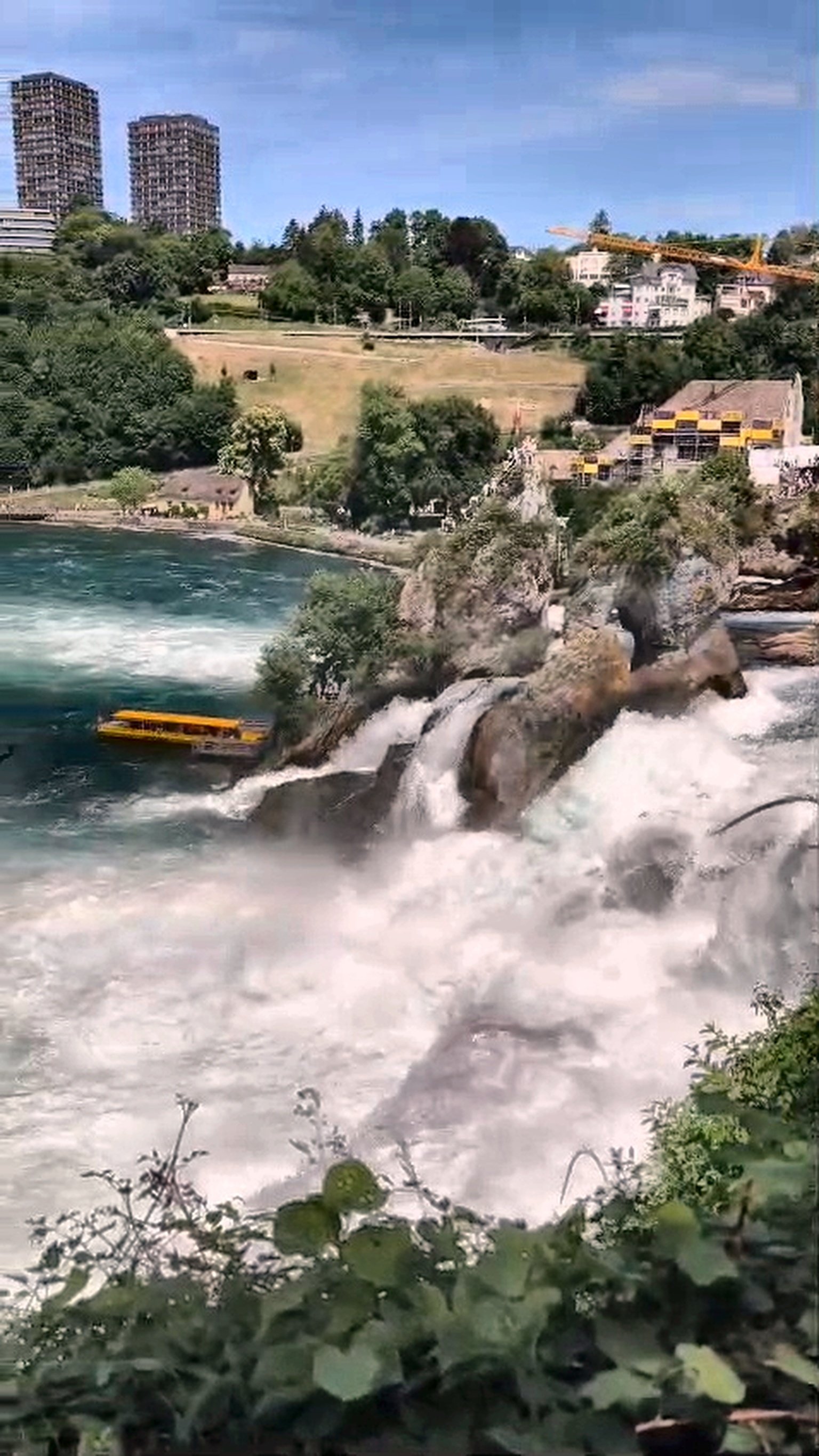 Yellow tour boat approaching the Rhine Falls cascade on a day trip from Zürich
